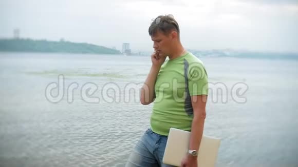 夏天一个男人拿着笔记本电脑站在水里视频的预览图