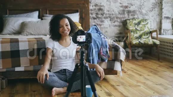 微笑卷曲的非洲裔美国女孩录制视频博客她的衣柜旅行与dslr相机在家视频的预览图