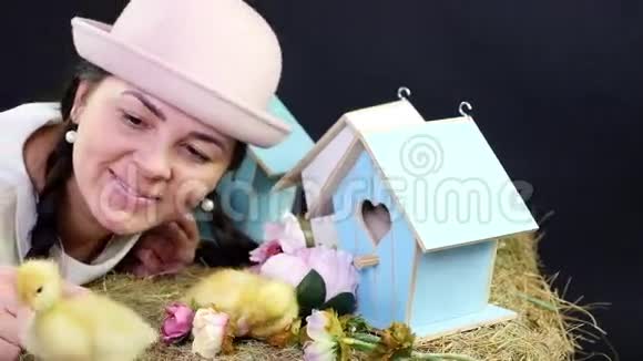 肖像一个漂亮的年轻女人有两条辫子戴着一顶有趣的粉红色帽子和小黄鸭玩耍在里面视频的预览图