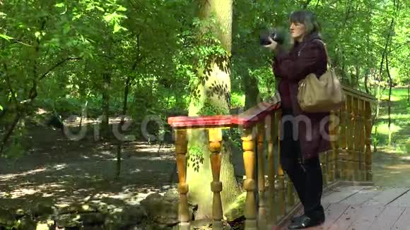 一个女人正拿着相机站在森林里视频的预览图