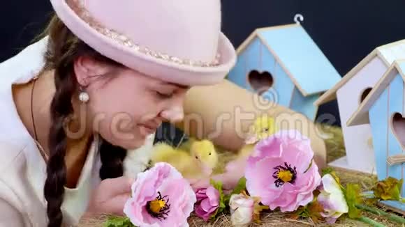 肖像一个漂亮的年轻女人有两条辫子戴着一顶有趣的粉红色帽子和小黄鸭玩耍在里面视频的预览图