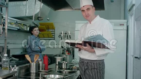 男厨师拿着菜谱厨师实习生点头赞许视频的预览图