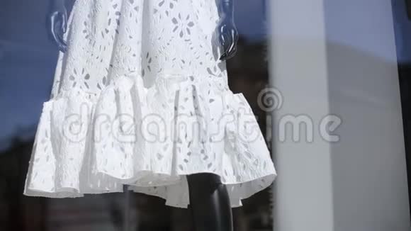 在阳光下陈列室的玻璃后面摆着白色衣服的模特视频的预览图