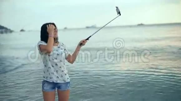 开朗的黑发女人在美丽的海滩上拍照视频的预览图