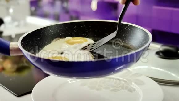 女人的手把炒鸡蛋放在锅里试图把食物和菜肴分开视频的预览图