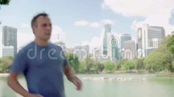 男子跑步者在公园慢跑适合男性运动健身跑步训练在他的智能手机上聊天视频的预览图