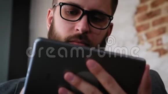 迷人的年轻人与数字平板在柔和的自然光一个留着胡子的时髦的现代年轻人用视频的预览图