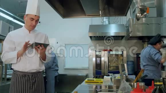 厨师在专业厨房的数码平板电脑上检查食谱视频的预览图