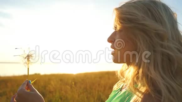 女人在夕阳下吹蒲公英视频的预览图