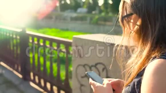 日落时分女人在街上散步时使用智能手机后景视频的预览图