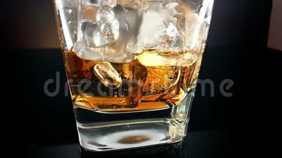在杯中加入黑色背景的冰块喝威士忌放松时间视频的预览图