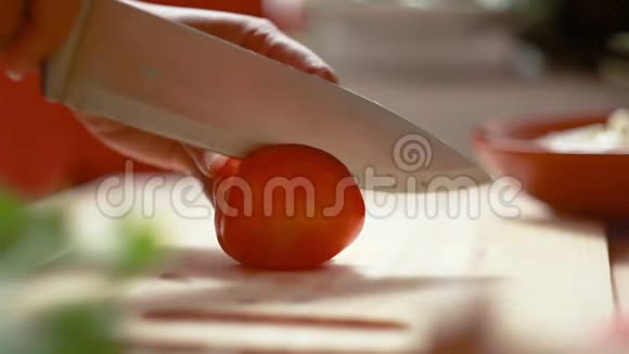 在准备烹饪的木切割板上用菜刀滑切新鲜番茄的女人的手视频的预览图