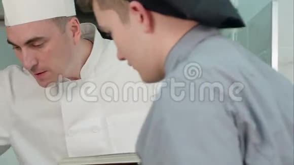 年轻的男性学员在看厨师长做饭视频的预览图