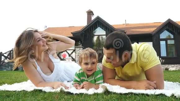 幸福的一家人躺在公园的草地上笑视频的预览图