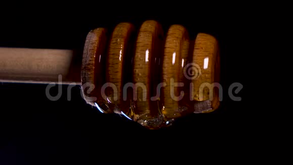 蜂蜜从特殊的蜂蜜勺或蜂蜜勺落在黑色的海滩上视频的预览图