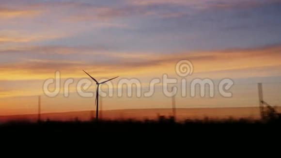 用风力发电机在乡村上空日落从一辆旅行车的窗户看风景视频的预览图