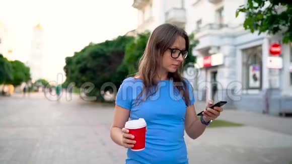 女人用智能手机喝着咖啡走在街上视频的预览图