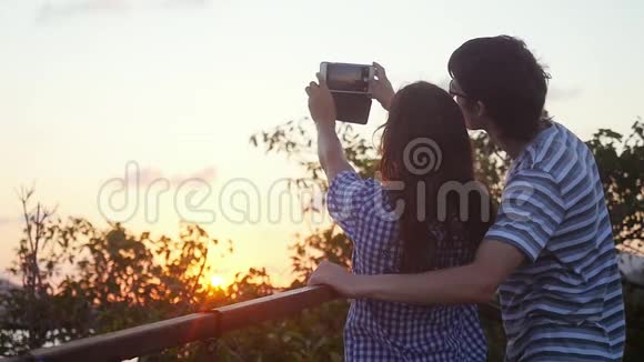 浪漫夫妇在山顶度假时在日落前拍摄自拍视频慢动作1920x1080视频的预览图
