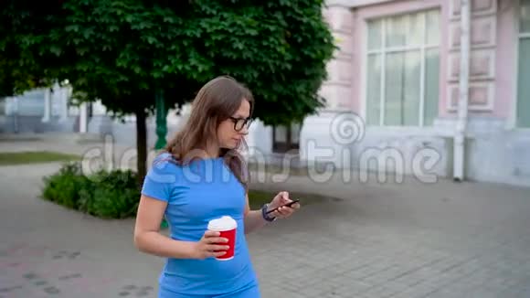 女人用智能手机喝着咖啡走在街上视频的预览图