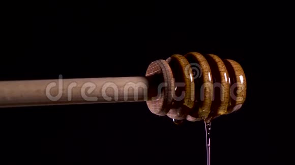 蜂蜜从特制的蜂蜜勺或蜂蜜勺掉落在黑色的海滩上视频的预览图