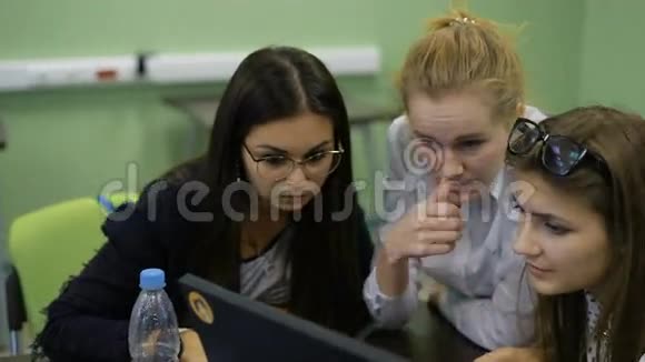 年轻的男女学生坐在办公桌前与电脑合作看监视器讨论和准备视频的预览图