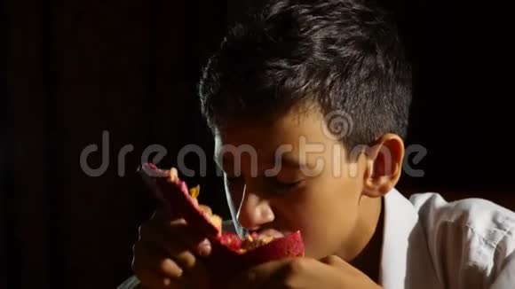 小饥饿的男孩一个素食主义者晚上贪婪地吃石榴4K慢动作视频的预览图