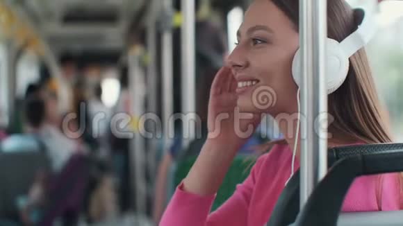 一位年轻女性乘客在公共交通工具上享受旅行的肖像戴着耳机坐在现代电车上视频的预览图