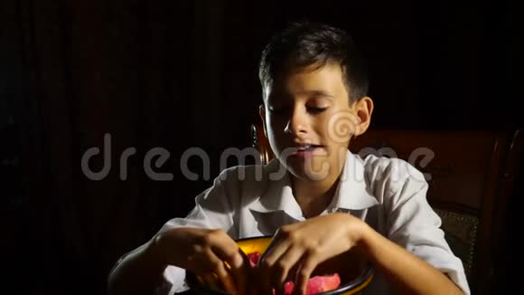 小饥饿的男孩一个素食主义者晚上贪婪地吃石榴4K慢动作视频的预览图