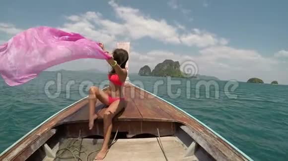 美丽的女子坐在泰国的小船上鼻子动作镜头轻拍扬起粉红的帕雷欧少女开心的笑视频的预览图