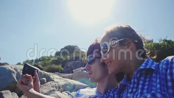 年轻漂亮的夫妇戴着太阳镜在美丽的山上自拍有着明亮的耀斑效果慢慢视频的预览图