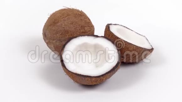 一整个椰子和两半美味的果肉旋转在白色孤立的背景可循环无缝视频的预览图