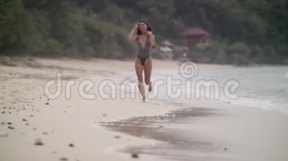 穿着泳装留着长发的迷人女孩穿着白色的沙滩跑步视频的预览图