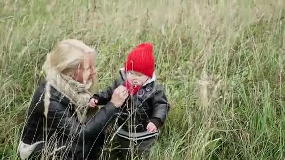 金发的妈妈和儿子走在高高的草地上视频的预览图