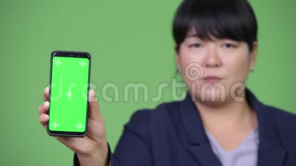快乐超重的亚洲女商人展示电话视频的预览图