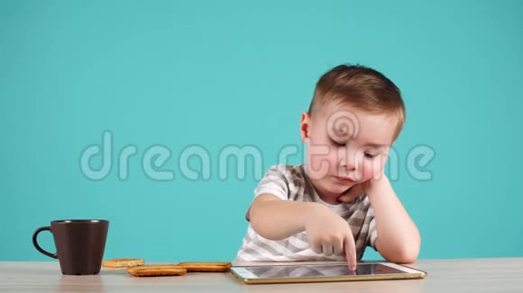 可爱的小男孩在蓝色背景上使用平板电脑视频的预览图