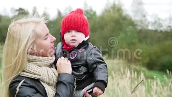 金发的妈妈和儿子走在高高的草地上视频的预览图