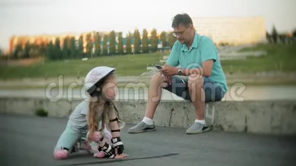父亲和女儿骑着溜冰鞋女孩学习溜冰摔倒父亲教女儿骑马视频的预览图