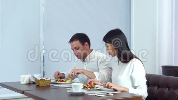 年轻夫妇在咖啡馆里吃午饭而服务员则提供更多的食物视频的预览图