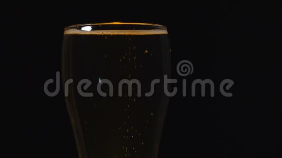 在黑色背景上的玻璃杯里放冷光啤酒快来点啤酒一杯啤酒视频的预览图