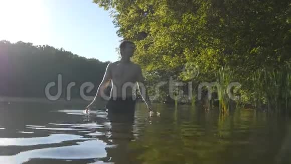 年轻人在夏天站在水里放松他在河边休息视频的预览图