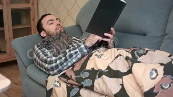 年轻人生病躺在沙发上看书视频的预览图
