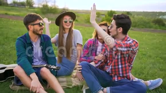 四个嬉皮士坐在草地上野餐他们给对方五个视频的预览图