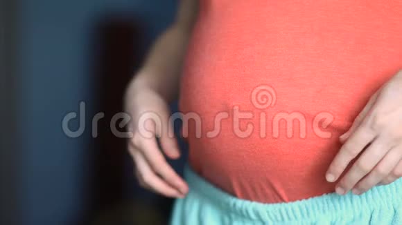 年轻的孕妇展示她的大肚子未来的孩子蓝色的色调稳定的凸轮慢镜头视频的预览图