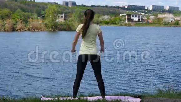 健身女孩在河边户外运动在令人惊叹的自然景观中做深蹲运动适合年轻女性视频的预览图