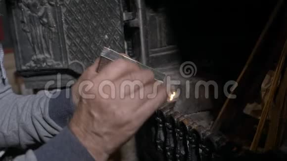 老人用手缓慢地通过火柴点燃壁炉中的火视频的预览图