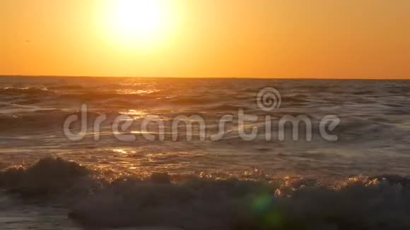 日出或非常美丽的日落在海滨沙滩和海浪拍打着海滩泡沫大风暴波视频的预览图