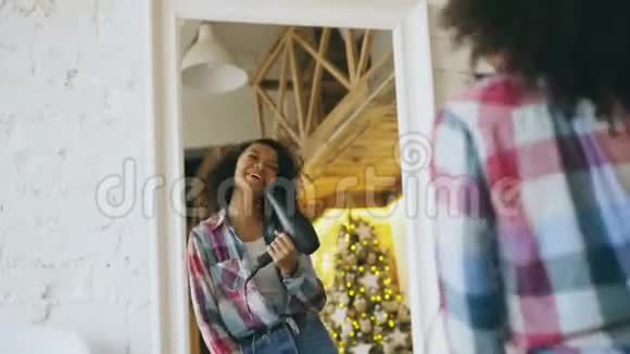 滑稽可笑的非裔美国女孩在家里用吹风机在镜子前跳舞唱歌视频的预览图