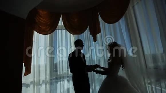 富丽堂皇的豪华新郎新娘站在窗前视频的预览图