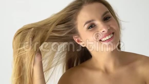 迷人的微笑女性肖像与长金发听到看镜头在白色背景视频的预览图