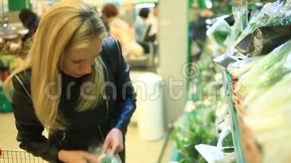 一个女人在蔬菜货架上的超市里买蔬菜和水果男人选择绿色视频的预览图